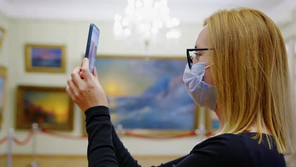 Blonde Girl in Mask Takes Pictures of Paintings