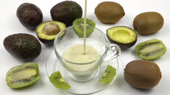 Kiwi, avocado and smoothie in a glass cup are on white table