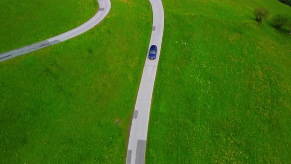 Volkswagen golf driving on an alpine road surrounded by green fields in Austria. alt