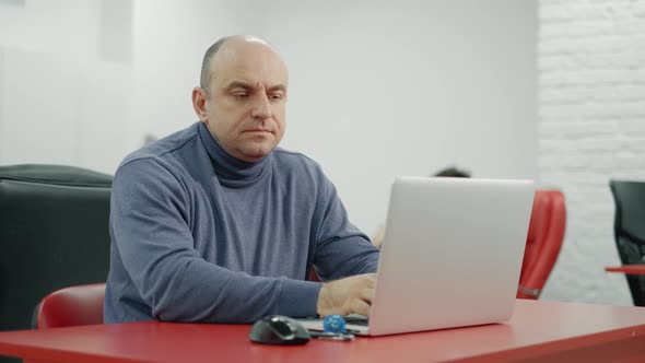 Mature Programmer Man Is Working on Laptop in the Office alt