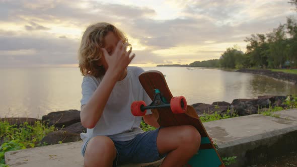 Silhouette Happy Child Portrait of Young Stylish Skater Boy Holding His Skateboard Outdoors alt