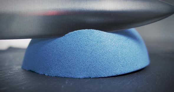 Hemisphere of blue kinetic sand is cut with a large knife. Relaxation techniques. Close-up. alt