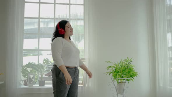 Fat woman or plus size is relaxing listening to music inside the house, she stands rocking softly.