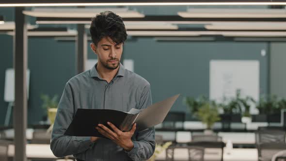 Young Indian Arab Man Analyst Accountant Manager Male Businessman Checking Document Folder alt