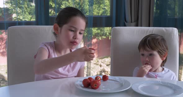 Cute Children Eating Fresh Ripe Strawberries at Home