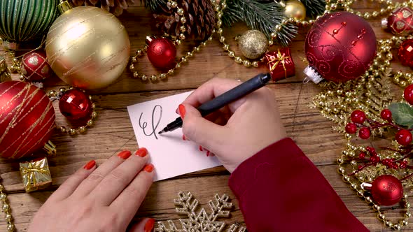 Woman's hand writing BIG SALE on a card near Christmas decorations alt
