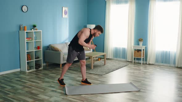 Man Is Training at Home Using Smartphone alt
