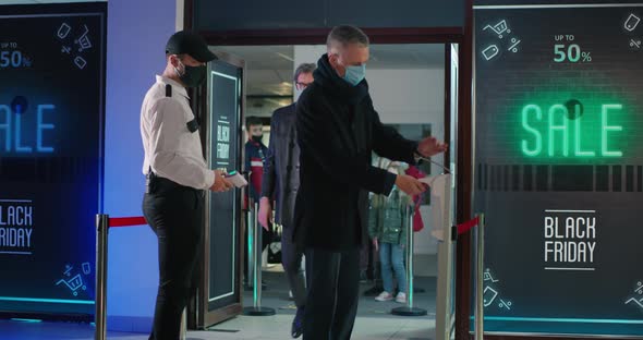 Security Guards Checking Temperature of People in Queue alt