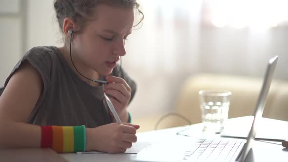 A Girl Student at Home Has a Video Call and Speaks Holding a Microphone of the Headphones alt