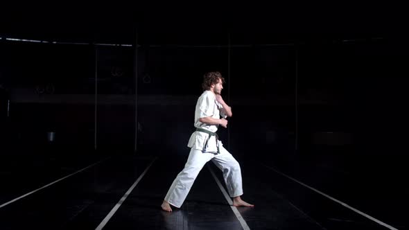 Young Man in Kimono, Performing Karate Bow Before Practicing. Black Background