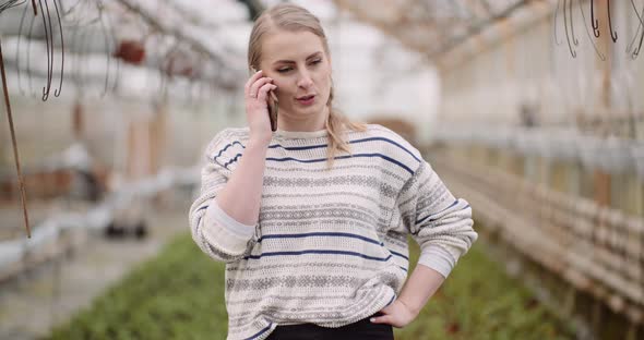 Agriculture - Female Gardener Using Mobile Phone in Greenhouse alt