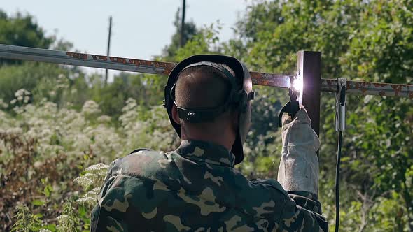 Slow Motion Backside Handyman Welds Plank of Metal Fence alt