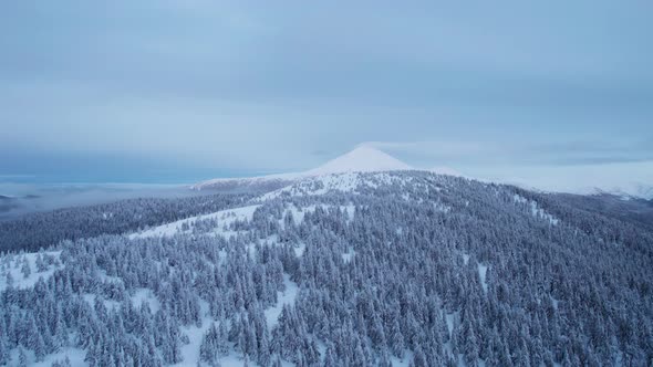 Drone Rising Above Hill Revealing Mountain Top Covered in Snow