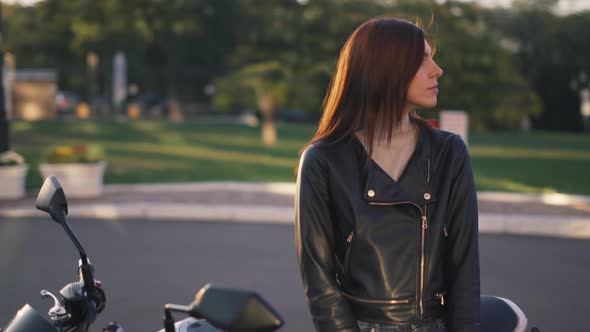 Beautiful Young Redhaired Woman Motorcyclist in a Leather Jacket on Bike alt