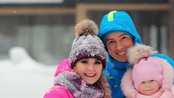 Happy Family Poses for Camera Standing on White Snow alt