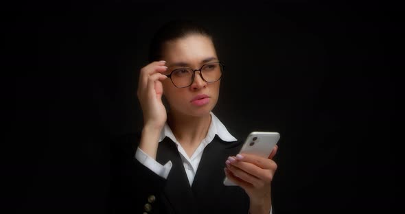 Thoughtful Business Woman Rests Her Chin and Holds a Cell Phone in Her Hands alt