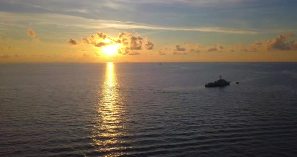 Aerial flight at stunning sunset over blue ocean along a ship in Mabul, Malaysia alt