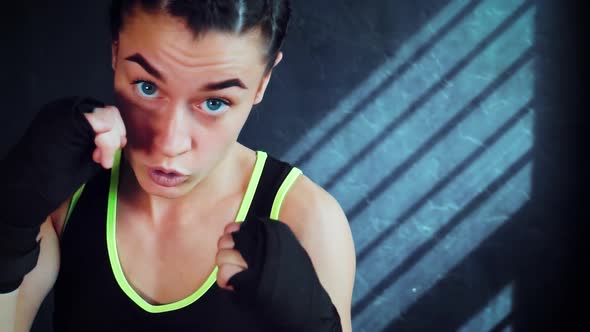 Female Boxer Looking at Camera and Practicing Punches in Gym alt