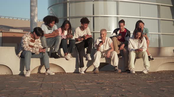 Multicultural Group of Teenager Friends Using Cellphones and Social Media Students Sitting in alt