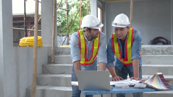 Young Asian engineers and caucasian engineer colleagues at site inspector and discuss together alt