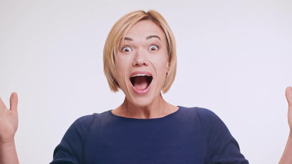 Blonde Beautiful Middleaged Woman Loudly Saying Wow and Smiling at Camera Standing on White alt