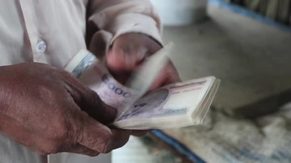Close up video of the hands of a man holding local currency in the countryside in Cambodia alt