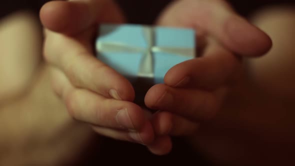 Man Holds Out a Gift in a Blue Box