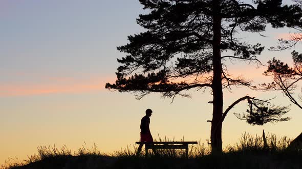 Silhouette of Lonely, Depressed Man, Sitting Down on Bench, Sunset Colors alt