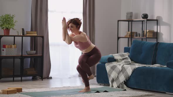 Hatha Yoga Training at Home Woman is Standing in Garudasana Lady is Performing Eagle Position alt