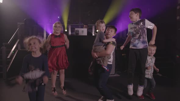 Kids Jumping Up and Down and Dancing at a Party With Bright Disco Lights - Ungraded alt