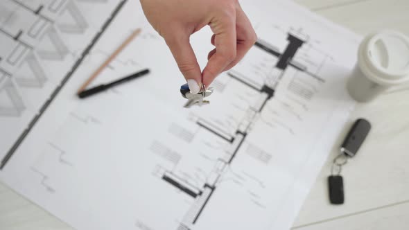 The Hand Holds the Keys To the House. Against the Background Architectural Plan of the Apartment  alt