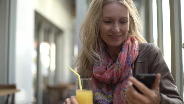 Woman using smart phone while drinking juice