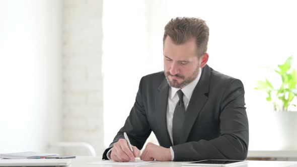 Young Businessman Having Disappointment While Writing on Paper alt
