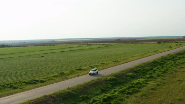 Aerial View of a Car Driving on a Country Road alt