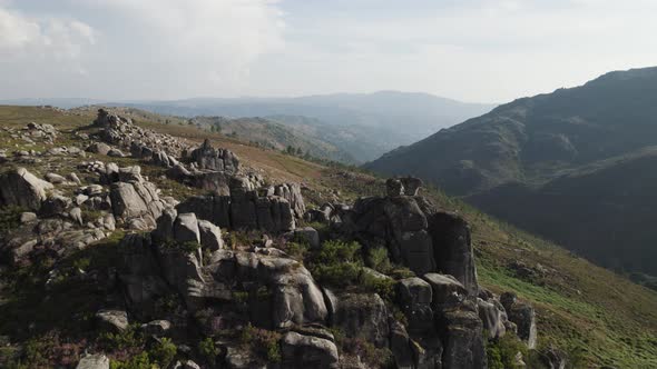 Flying through stones on hilltop, idyllic scenery with valley and mountain layers, Gerês, Portugal