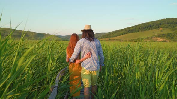 Couple walking in a reed field in the afternoon alt