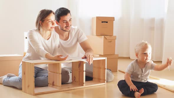 Family Together at Living Room of New Apartment Assembling Furniture alt