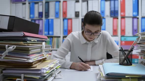 Woman working in the office and piles of paperwork