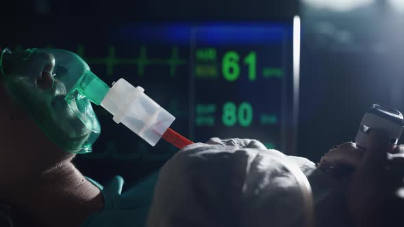 A Female Patient in Medical Mask is Breathing Oxygen Support in a Hospital Next to Heart Rate alt