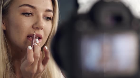 A Pretty Makeup Artist Is Applying Lipliner on Her Lips alt