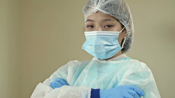 Asian Female Doctor or Nurse in Protective Uniform and Latex Gloves Prepared for Procedures or