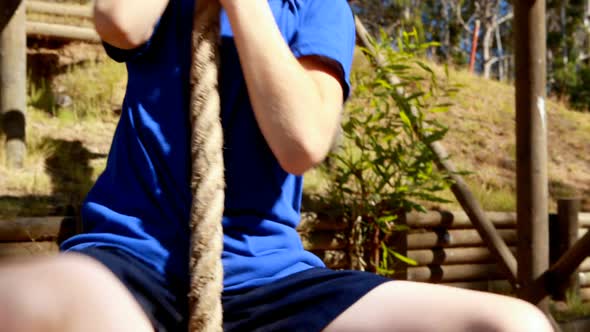 Determined girl climbing rope during obstacle course alt