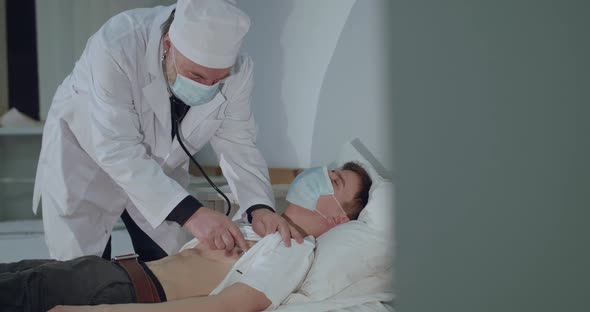 Doctor Listens to the Sick Boy's Breath with Phonendoscope on Chest in Hospital alt