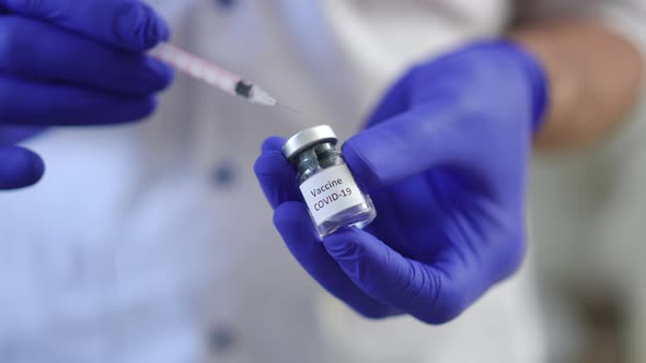 Male Hands Filling Syringe with Covid19 Vaccine in Slow Motion Closeup alt