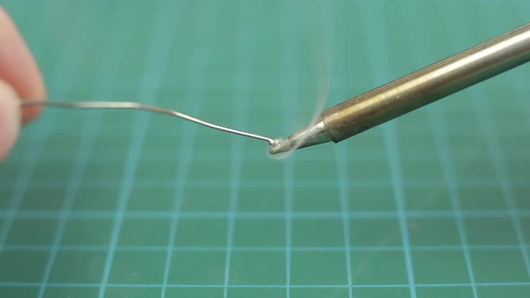 Melted Solder Wire Over a Hot Soldering Iron Tip. Close Up.