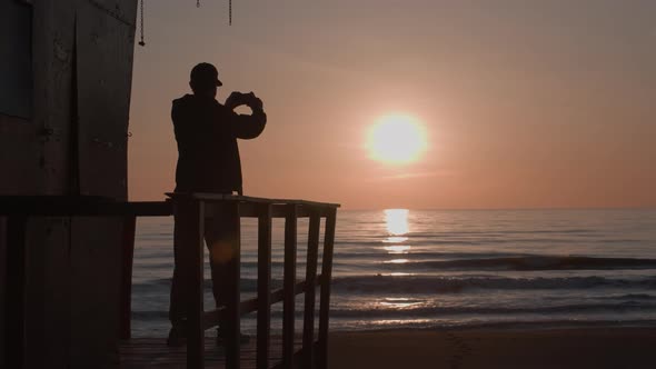 Silhouette of Adult Man Alone on Old Wooden Lifeguard Tower Shoot Amazing Sunset