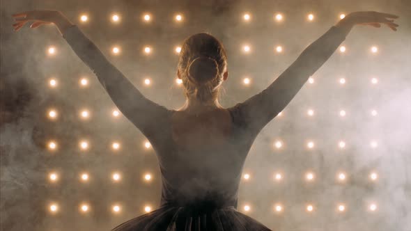 Silhouette of Ballerina in Black Dress Is Dancing Ballet in the Dark Studio.