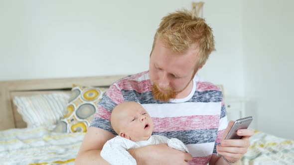 a man with a crying baby in his arms looking for information on the phone