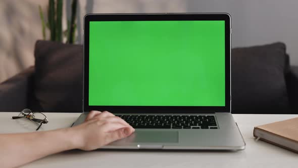 Close-up On the Hands of the Female Specialist Works on a Laptop Computer with Mock-up Green Screen