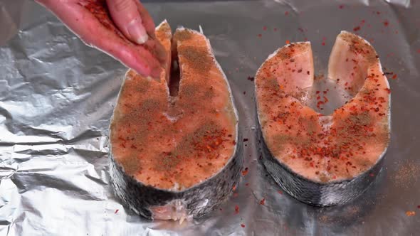Seasoning salmon steak. Chef adding spices on raw salmon steak before baking. Raw salmon alt